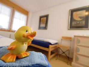 Una habitació amb un llit, una taula petita, una cadira, un aparador i un quadre amb marc a la paret.