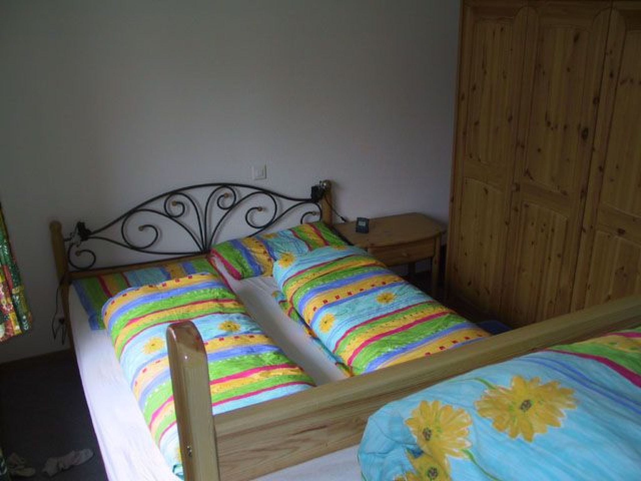 A single-bed room with a wooden headboard, a nightstand, and a wardrobe.