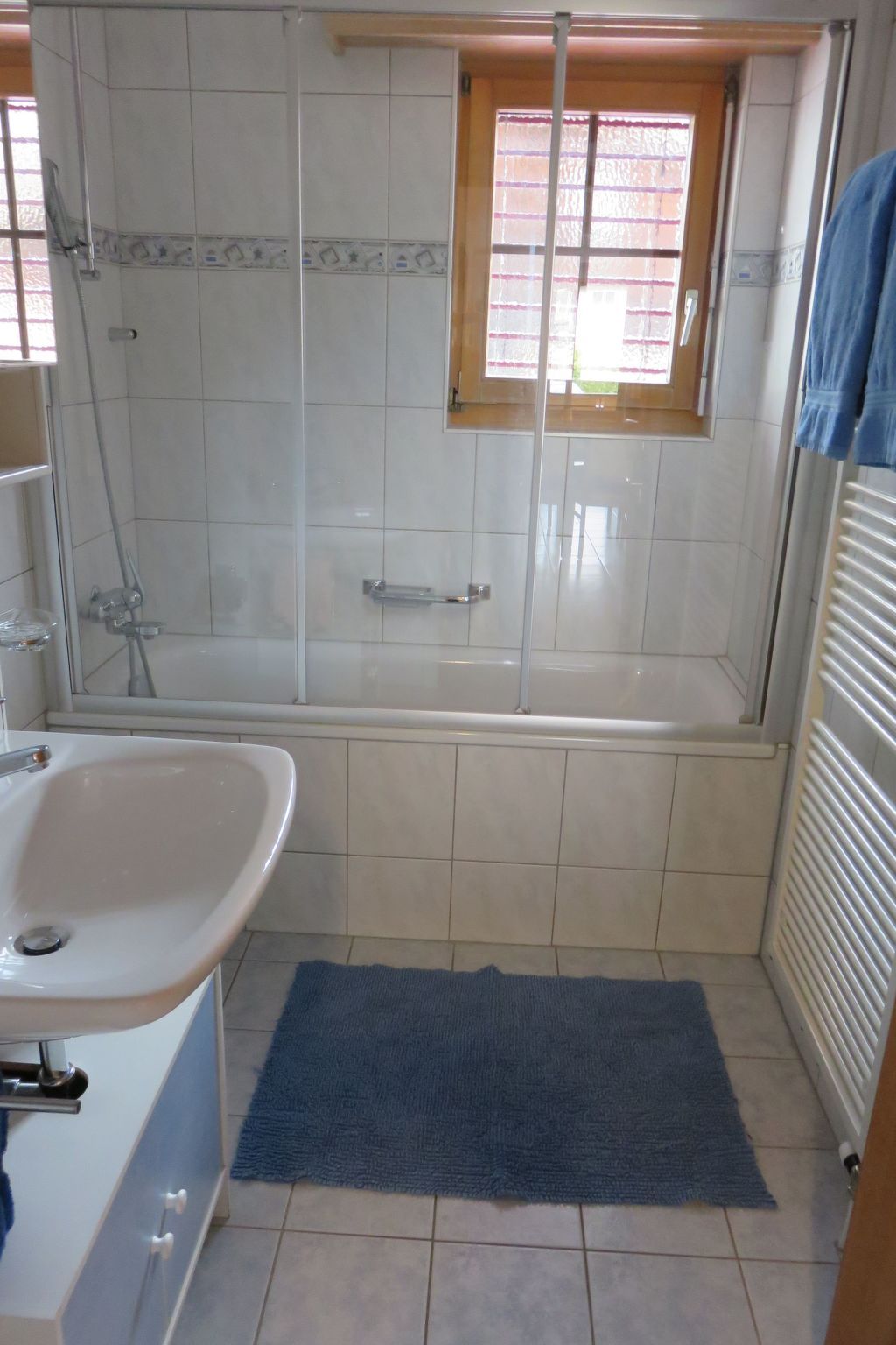 A bathroom with a bathtub, a shower, a sink, and a window.