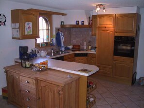 A kitchen with wooden cabinets, a coffee maker, and a fruit bowl on the counter. - Sierra Vista 16, (Grächen), 5003 by Interhome (Grächen)