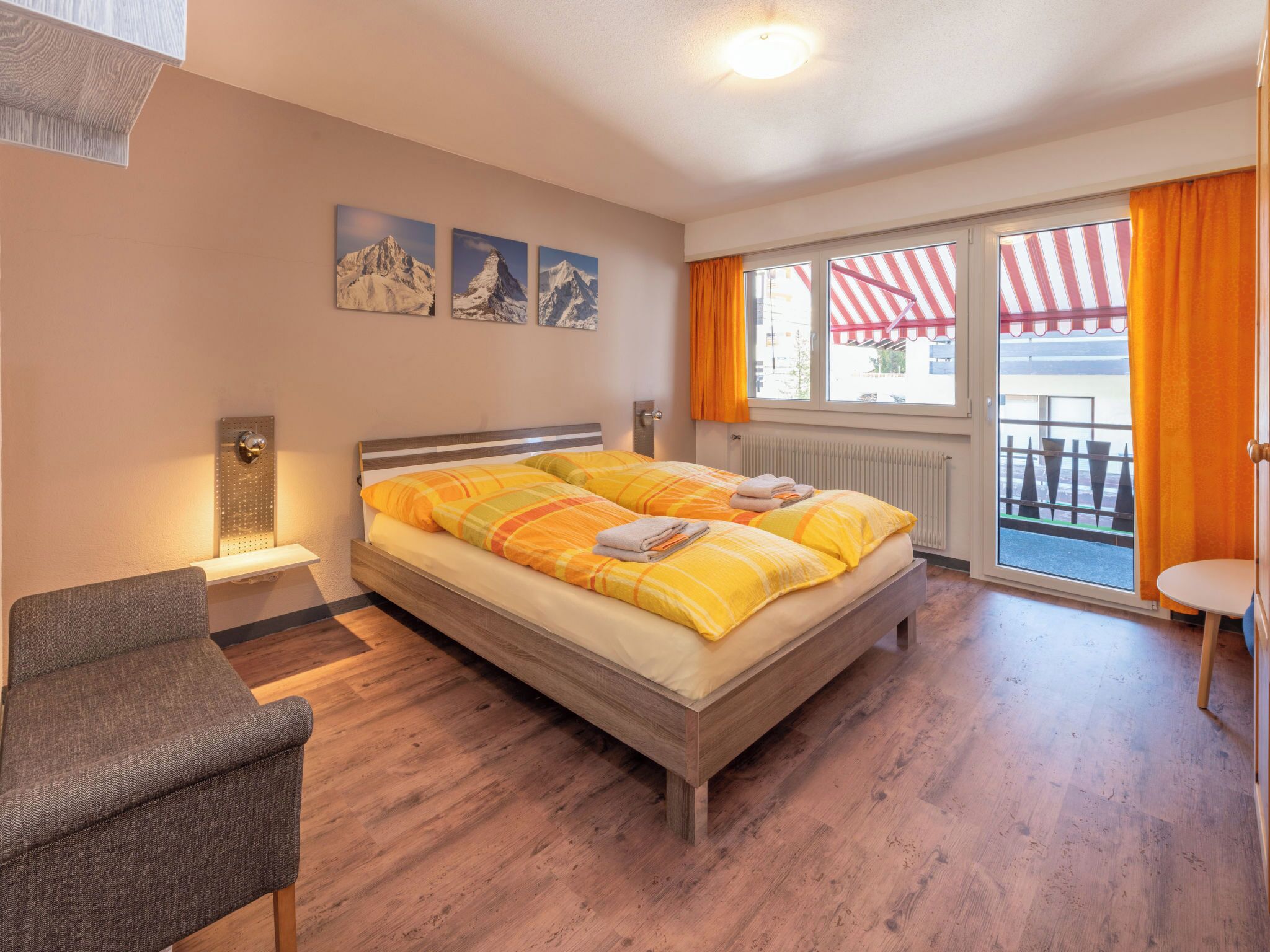 Une chambre d’hôtel avec un lit, une chaise, une fenêtre avec des rideaux et un radiateur.