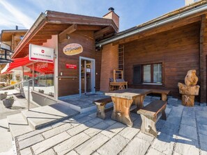 Un edificio de madera con toldo rojo, asientos al aire libre y un letrero para una tienda llamada 'Z'Pfünderli'.