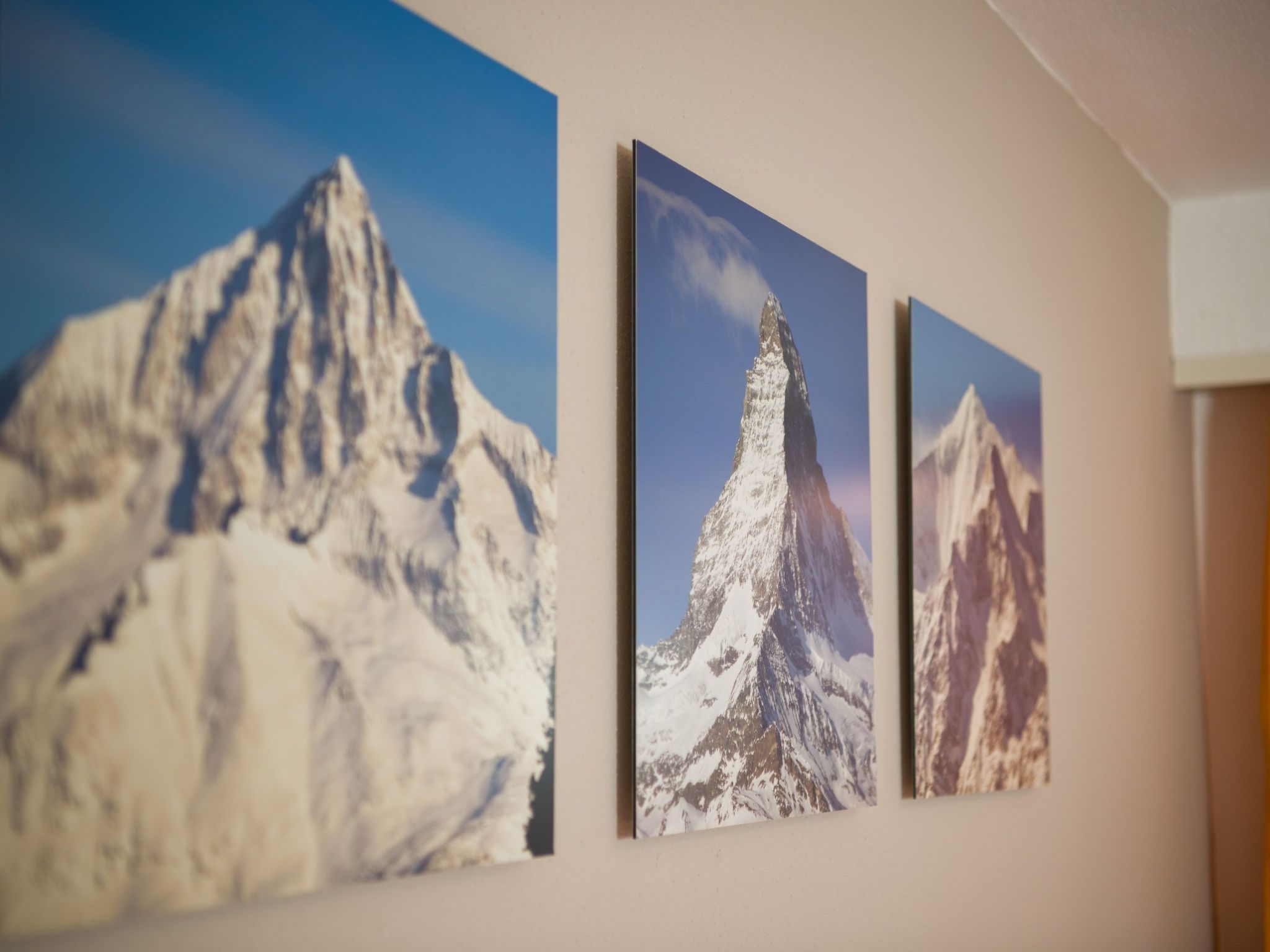 Three framed mountain photographs on a wall.