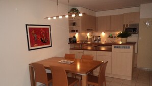 A modern kitchen with a dining area, featuring a wooden table and chairs, a built-in oven, and a microwave. - Silberblick, (Grächen), by Interhome (Grächen)