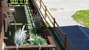A covered outdoor seating area with a wooden fence, a red awning, and a paved walkway. - Silberblick, (Grächen), by Interhome (Grächen)
