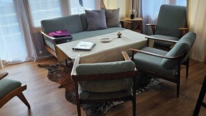 Uma sala de estar aconchegante com um sofá, duas poltronas, uma mesa de centro e um tapete.