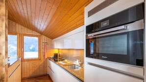 Cocina moderna con paredes de madera, horno integrado y ventana con vistas.