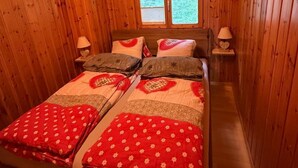 Una habitación con paneles de madera, una cama, dos lámparas de noche y un ventanal.
