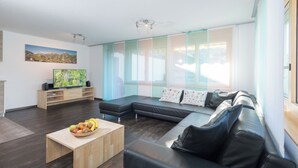 Un soggiorno moderno con un divano, un tavolino da caffè con della frutta, una televisione e un quadro appeso al muro.