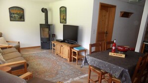 Una sala de estar con sofá, televisor, aparador de madera y una mesa de comedor con sillas.