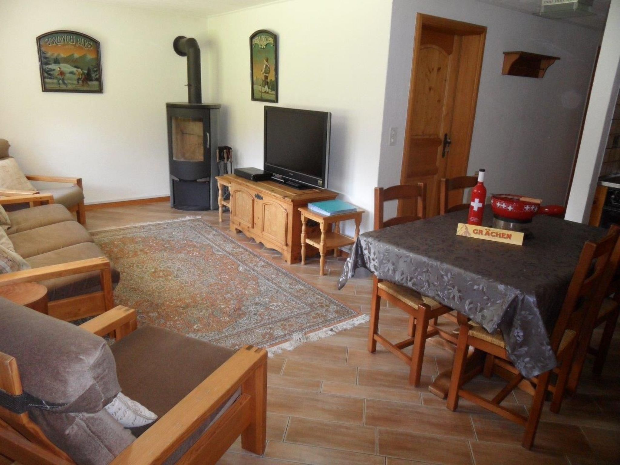 Un salon comprenant un canapé, un téléviseur, une cheminée et une table à manger avec des chaises.