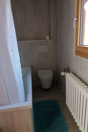 A bathroom with a toilet, a towel rack, a radiator, and a window. - Ferienwohnungen Miranda, (Grächen), by Interhome (Grächen)