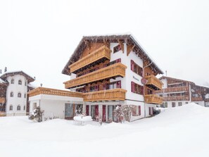 Ein mehrstöckiges Hotel mit Balkonen und verschneiter Landschaft.