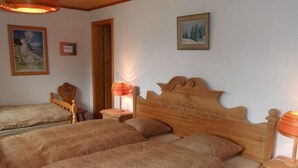 Ein Zimmer mit zwei Holzbett, einem Holzstuhl, einem Nachttisch mit Lampe und einem gerahmten Bild an der Wand.
