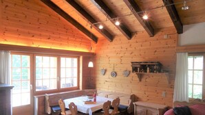 Ein Holzinterieur mit Esstisch, Stühlen, einer Couch und einem Schrank.