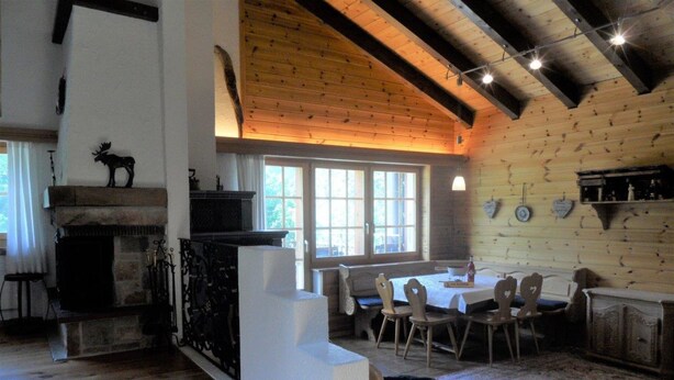 Ein rustikales Interieur mit Kamin, Holzbalken, einer Essecke und einer Treppe.