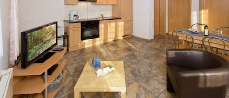 A compact living space with a kitchen, dining area, and a seating area with a television.