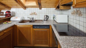 Eine Küche mit Holzausstattung, einem Geschirrspüler, einer Mikrowelle und einem Spülbecken.