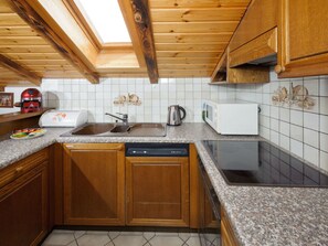 Eine Küche mit Holzausstattung, einem Geschirrspüler, einer Mikrowelle und einem Spülbecken.