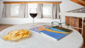 Ein runder Tisch mit einem Weinglas, einer Chips-Schüssel und einem Buch, auf dem Gläser stehen.