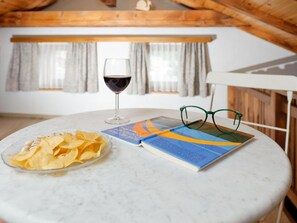 Ein runder Tisch mit einem Weinglas, einer Chips-Schüssel und einem Buch, auf dem Gläser stehen.