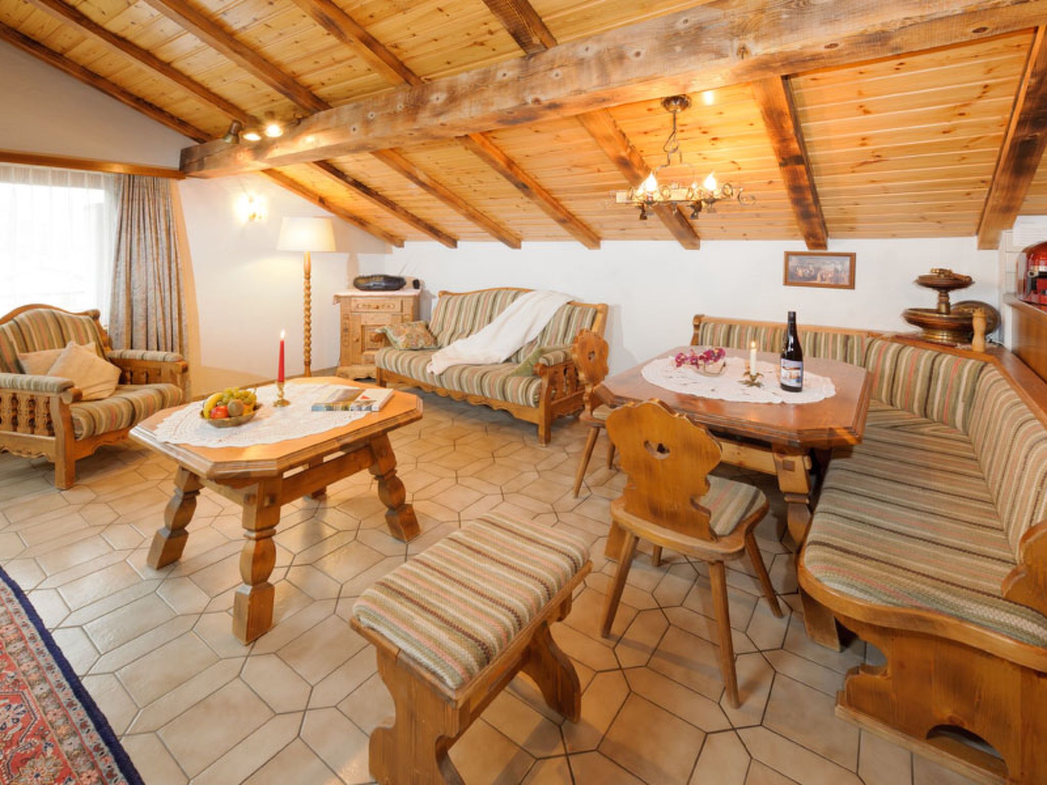 A cozy, rustic interior with wooden furniture, a dining table, and a chandelier.