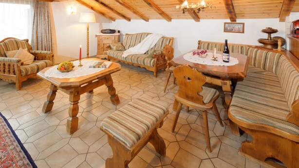 Ein gemütliches, rustikales Interieur mit Holmöbeln, einem Esstisch und einer Chandelüstere.
