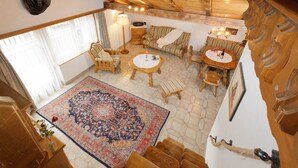 Ein geräumiges Zimmer mit großem Teppich, Holzmöbeln und einer Decke mit freiliegenden Balken.