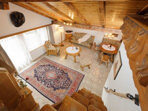 Ein geräumiges Zimmer mit großem Teppich, Holzmöbeln und einer Decke mit freiliegenden Balken.