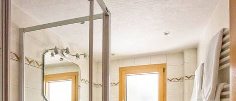 A bathroom with a glass shower enclosure, a sink, a toilet, and a towel rack.