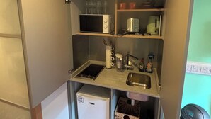 Una kitchenette compacta con microondas, tostadora, lavamanos y refrigerador pequeño.