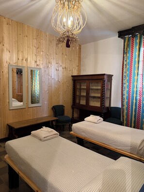 A room with two single beds, a wooden wardrobe, a mirror, a bench, and a chandelier. - Viale del Re 33: A Summer Fairy Tale Between the Sea and the Theater (Reggio Calabria)