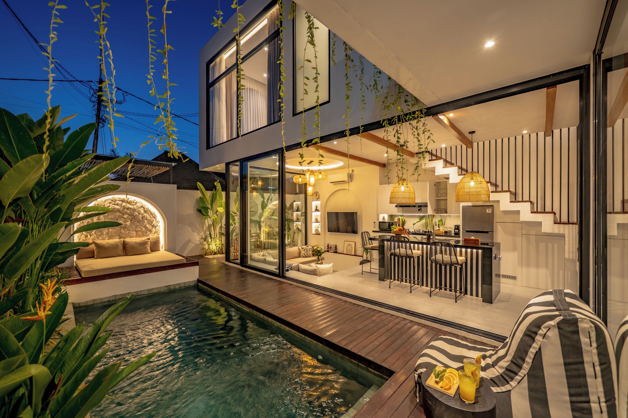 Una casa moderna con piscina, zona de comedor y escalera.