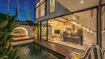 Una casa moderna con piscina, zona de comedor y escalera.