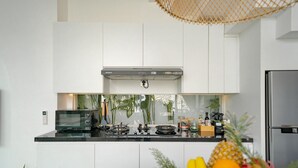 Een moderne keuken met witte kasten, een roestvrijstalen koelkast, een magnetron en een gasfornuis.