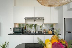 A modern kitchen with white cabinets, a stainless steel refrigerator, a microwave, and a gas stove. - Villa Scorpia 1 Bingin (Pecatu)