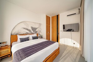 Ein modernes Schlafzimmer mit einem großen Bett, einem an der Wand befestigten Fernseher und einem Holzschrank.