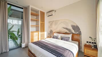 Een moderne slaapkamer met een groot bed, inbouwkasten, een wandairconditioner en uitzicht door een glazen deur.