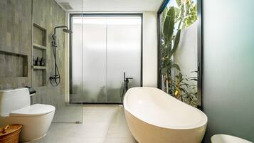 Un baño moderno con una bañera independiente, cabina de ducha con mampara de vidrio y un inodoro.