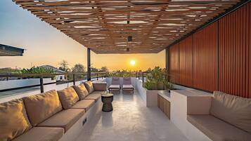 Een dakterras met een houten pergola, een zithoek en uitzicht op de zonsondergang.