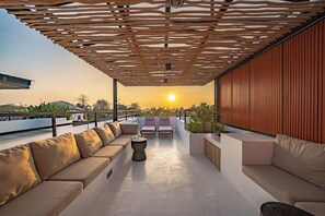 A rooftop terrace with a wooden pergola, seating area, and a view of the sunset. - Villa Scorpia 1 Bingin (Pecatu)
