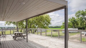A wooden deck with picnic tables and a view of a green landscape.
