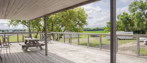 En træterrasse med picnicborde og udsigt over et grønt landskab.