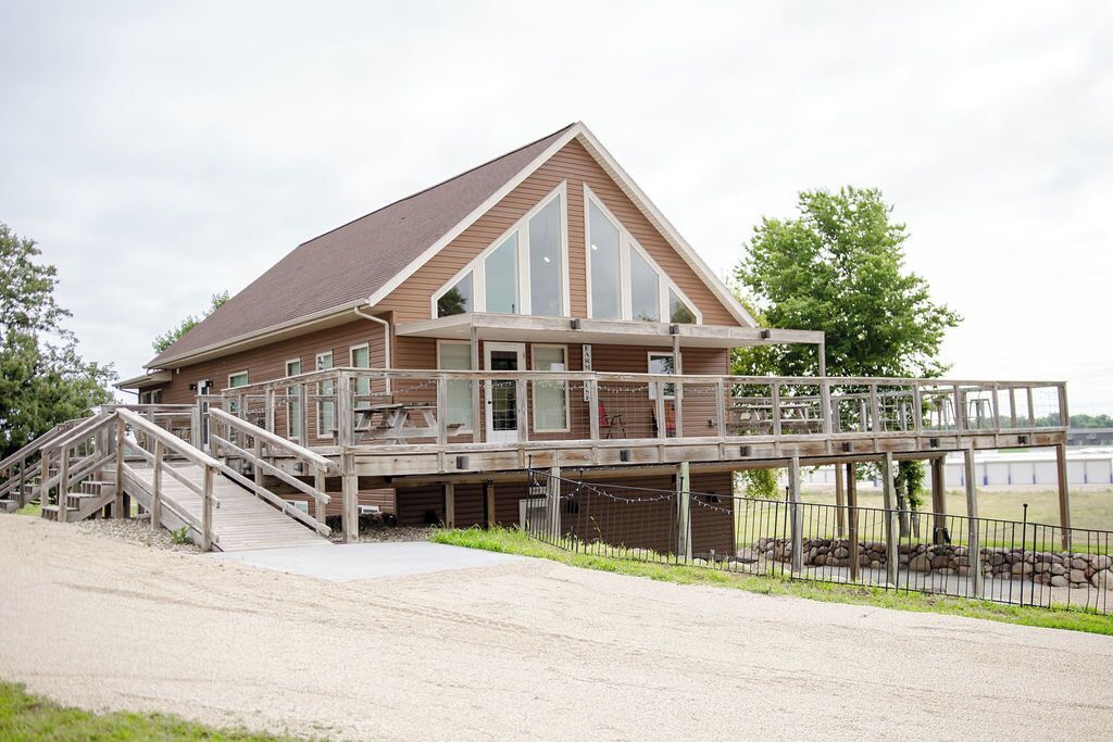 A building with a wooden deck, a staircase, and a view of the water.