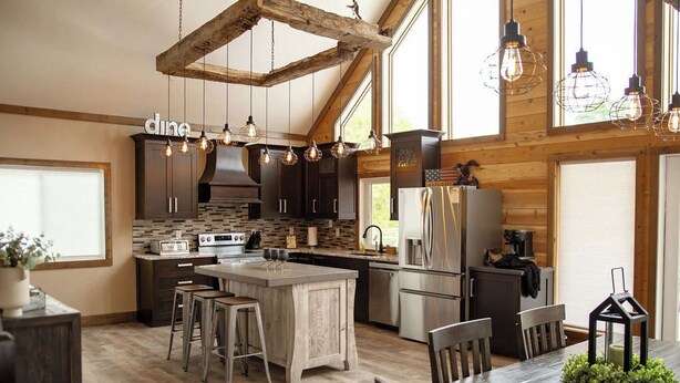 A spacious kitchen with wooden beams, a central island, bar stools, and pendant lighting.