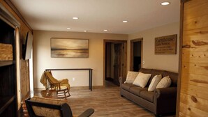 A cozy living room with a brown leather sofa, a wooden floor, and a painting on the wall.