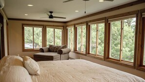 A bedroom with a large bed, a sofa, and a ceiling fan.
