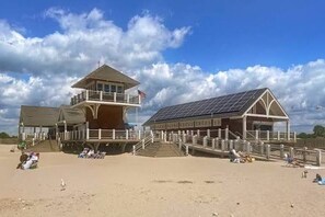 A beachside building with a balcony, a staircase, and a flag. - NEW! Saltaire Retreat - Walk to Beach - Beautiful Sand Hill Cove (Narragansett)