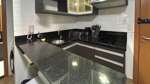 Una cucina con piano di lavoro in granito, lavello in acciaio inossidabile, pensili neri e cappa aspirante nera.