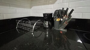 Una cucina con scolapiatti, macchina del caffè e portautensili sul piano di lavoro.